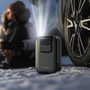 Spark hand portable air pump in black inflating a car tire in snowy outdoor setting